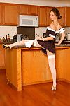 Youthful Eastern girl in maid\'s uniform and nylons strutting in kitchen
