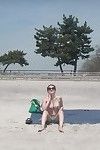 Busty brunette takes sunbath on public beach