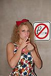Rebel girl with curly hair smoking under a no smoking sign