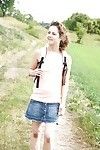 Young Euro girl baring shaved pussy underneath short skirt outdoors in field
