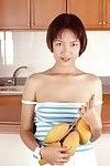 Vêtu Asiatique Avec Minuscule seins est posant dans l' cuisine Avec Propagation les jambes