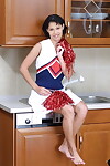 Smiley brunette pom-pom girl déshabillage et exposer Son marchandises dans l' cuisine