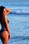 एकल लड़की के साथ काले बाल डाले एक तरफ उसके बिकिनी शीर्ष जबकि पर के समुद्र तट
