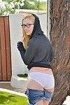 Nerdy teen in glasses and hoodie losing her cutoff denim shorts outdoors