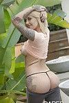 Tattooed blonde girl Emma Mae exposing big tits and thong clad ass outdoors